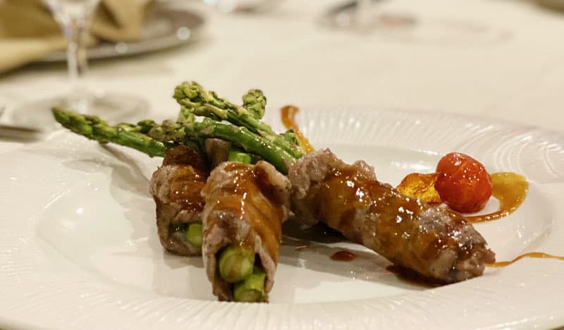 Beef rolls with grilled asparagus on a white plate