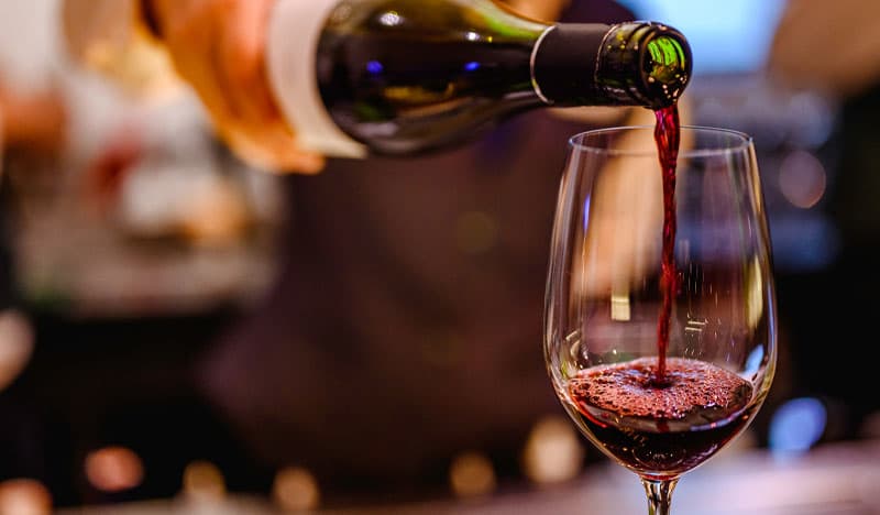Red wine being poured into a glass at the bar